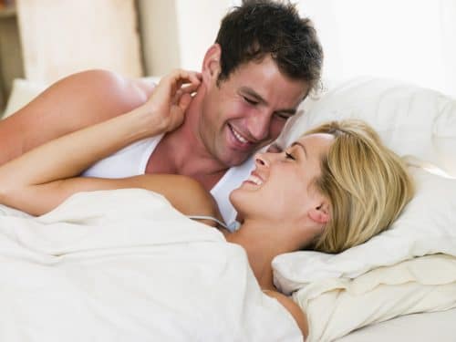 Couple lying in bed smiling